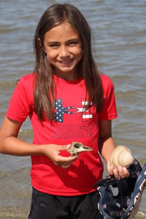 a young girl standing next to a body of water